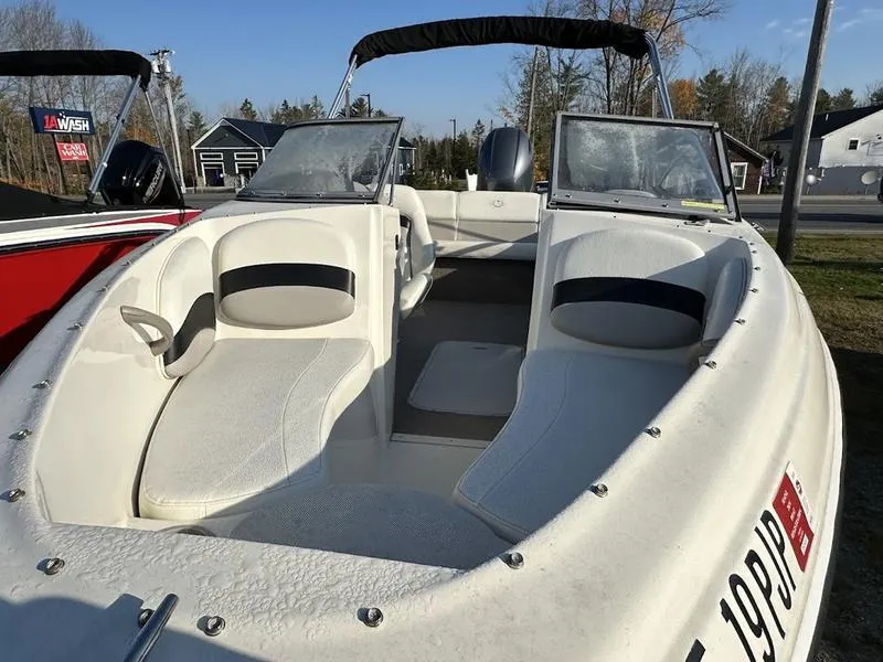 Slide: The Image of 2015 Stingray 191RX boat with white seating and windshield, parked outdoors. - 8