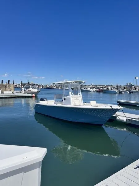 Slide: The Image of 2024 Sea Hunt Ultra 229 boat docked in a sunny marina. - 1
