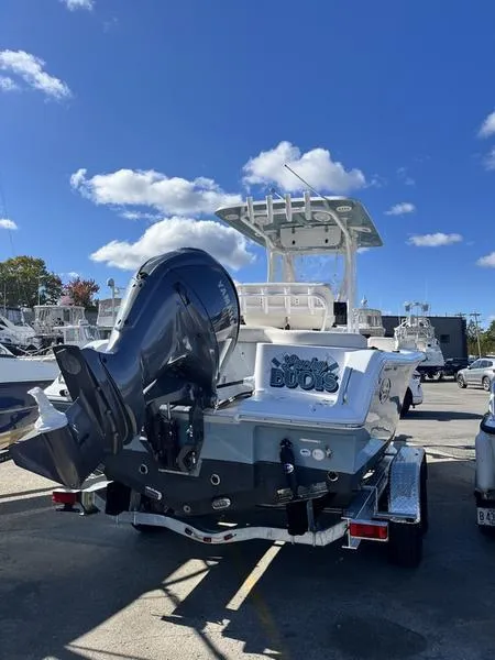 Slide: The Image of 2024 Sea Hunt Ultra 229 boat with powerful outboard motor, parked under a clear blue sky. - 3