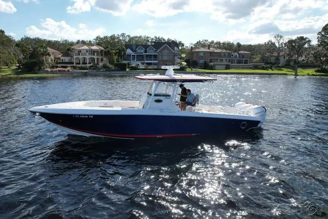 Slide: The Image of 2023 Fountain 34 CC boat on a serene lake with waterfront homes in the background. - 12