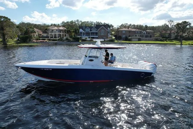 Slide: The Image of 2023 Fountain 34 CC boat on a serene lake with waterfront homes in the background. - 13