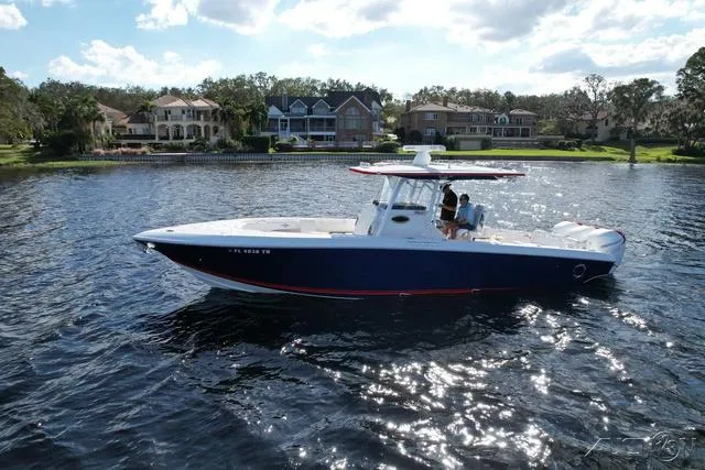 Slide: The Image of 2023 Fountain 34 CC boat cruising on a scenic lake near waterfront homes. - 7