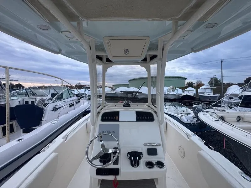 Slide: The Image of 2022 Grady-White 257 Fisherman boat interior, featuring helm and controls, docked among other boats. - 10