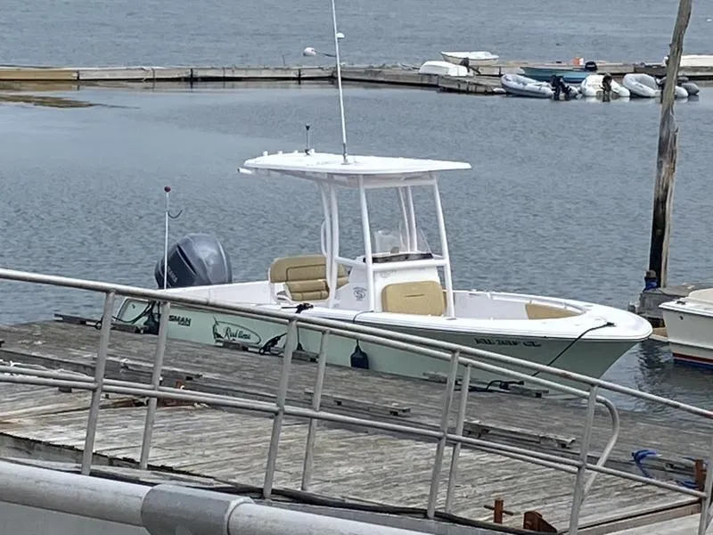 Slide: The Image of 2022 Sportsman 231 Heritage boat docked at a marina with calm waters. - 18