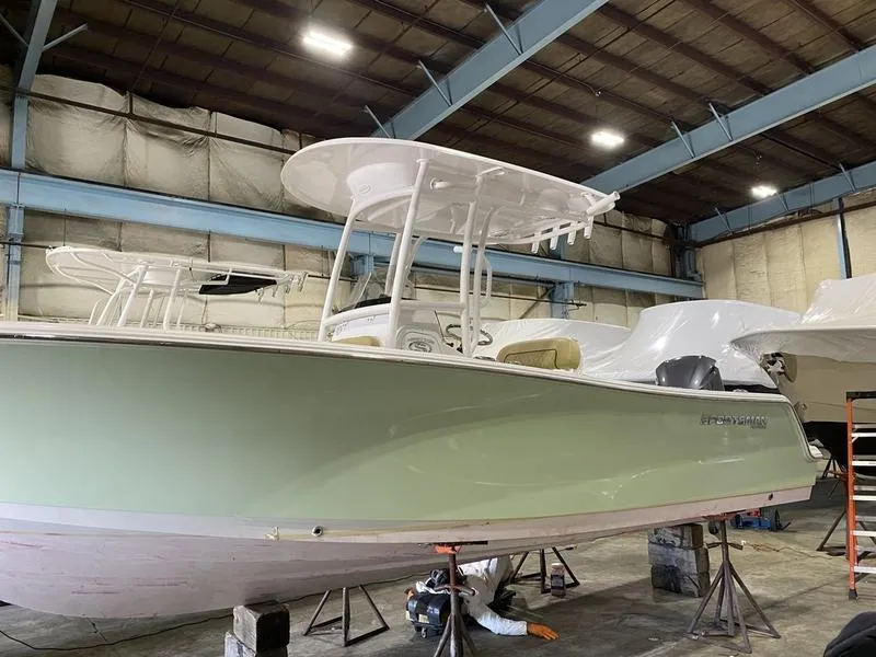 Slide: The Image of 2022 Sportsman 231 Heritage boat in a warehouse, light green hull, white T-top. - 9