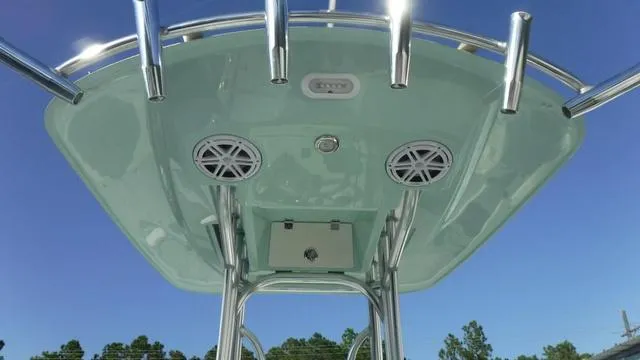 Slide: The Image of 2025 Pathfinder 2500 Hybrid boat T-top with speakers and rod holders against blue sky. - 30