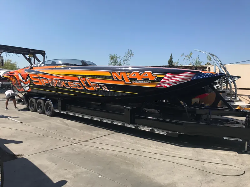 Slide: The Image of 2018 Daves Custom Boats M-44 on trailer, vibrant graphics, sunny day. - 5