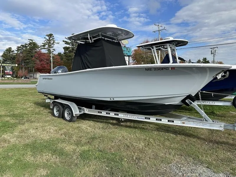 Slide: The Image of 2020 Sportsman 241 Heritage boat on trailer, parked on grass under a cloudy sky. - 22