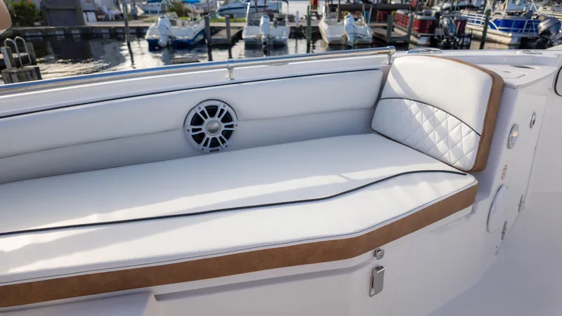 Slide: The Image of 2025 Stingray 216CC boat interior with white cushioned seating and speaker, docked at marina. - 12