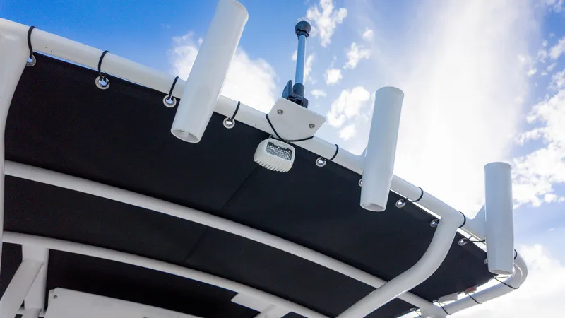 Slide: The Image of 2025 Stingray 216CC boat canopy with rod holders against a blue sky. - 17