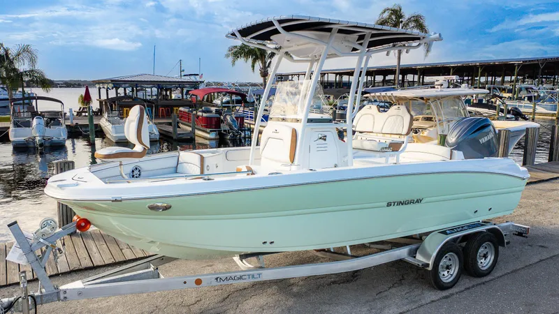 Slide: The Image of 2025 Stingray 216CC boat on trailer at marina, clear sky background. - 18