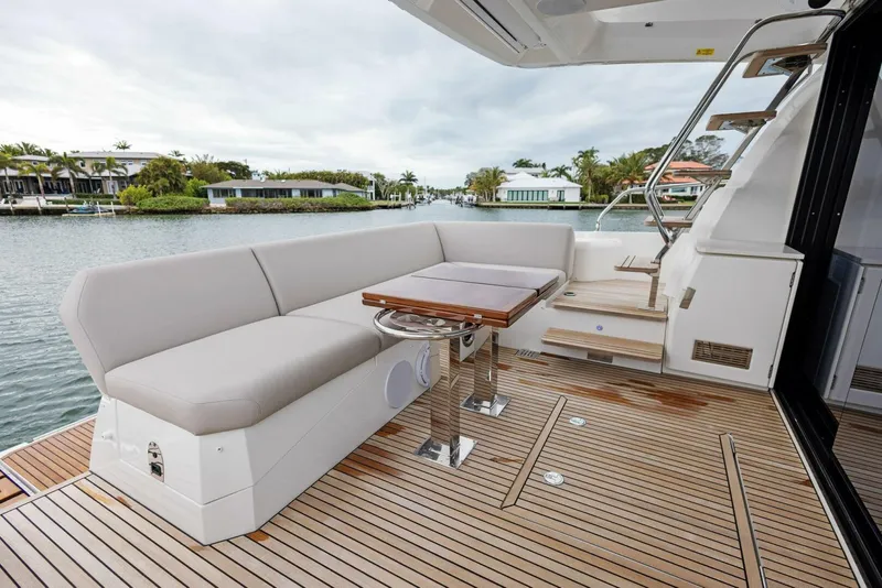 Slide: The Image of Luxury 2022 Prestige 520 yacht deck with seating and table, overlooking serene waterfront. - 29