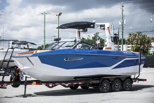 Slide: The Image of 2025 Nautique G25 boat on trailer, blue and white design, parked outdoors. - 1