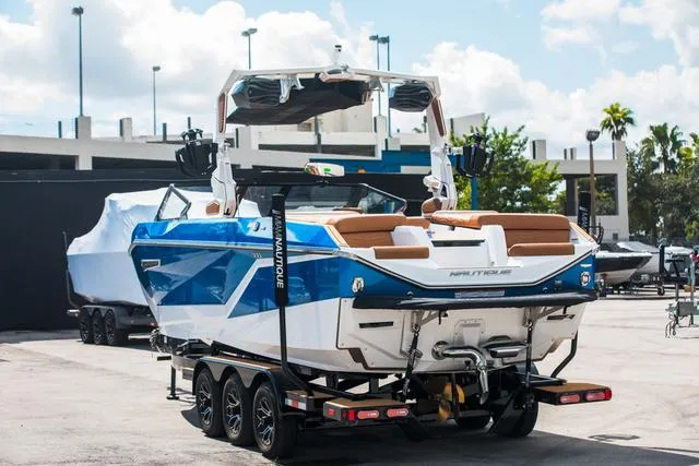 Slide: The Image of 2025 Nautique G25 boat on trailer, blue and white design, parked outdoors. - 4