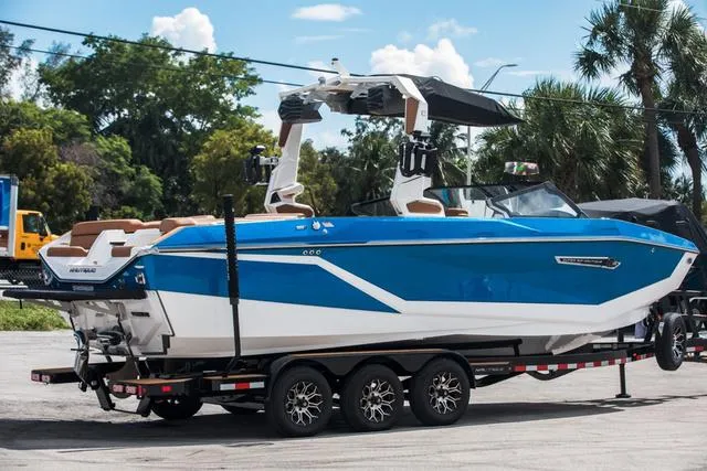 Slide: The Image of 2025 Nautique G25 boat on trailer, blue and white design, parked outdoors. - 6