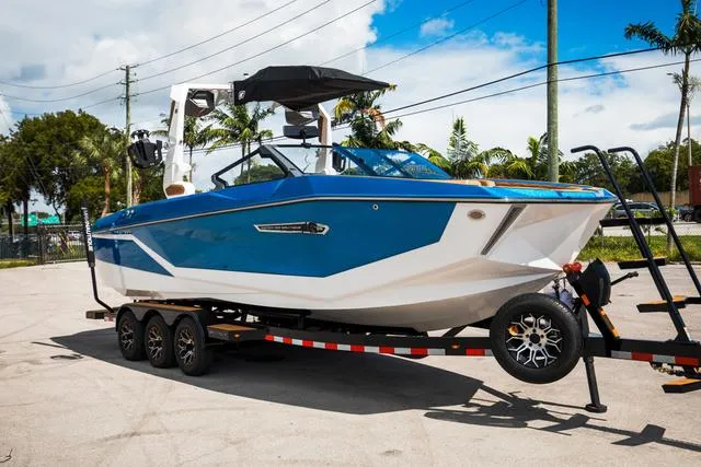 Slide: The Image of 2025 Nautique G25 boat on trailer, blue and white design, parked outdoors. - 9
