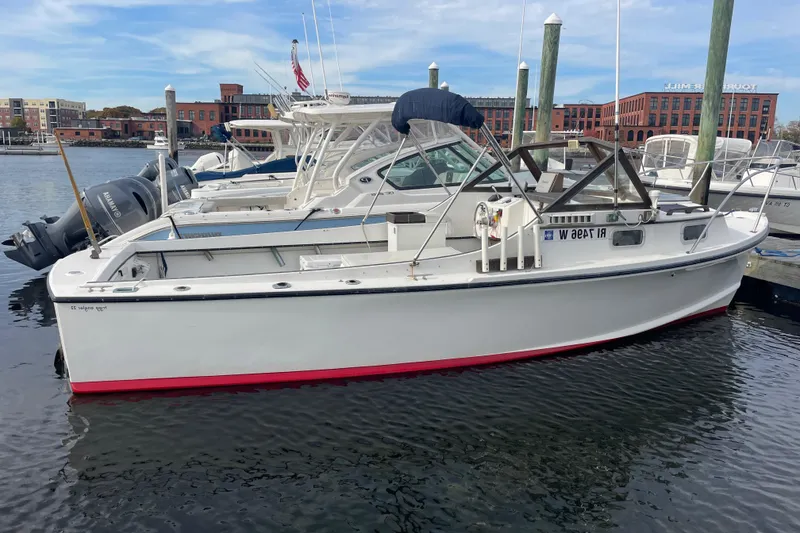 Slide: The Image of 1993 Tripp Angler 22 boat docked in a marina, featuring a white hull with red trim. - 2