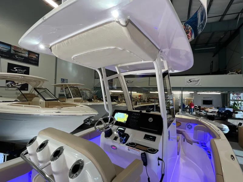 Slide: The Image of 2025 Scout 240 XSF boat interior with modern dashboard and seating in showroom. - 10