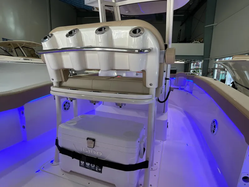 Slide: The Image of 2025 Scout 240 XSF boat interior with rod holders and cooler, illuminated by blue LED lights. - 15