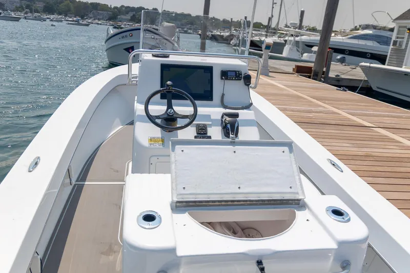 Slide: The Image of 2023 Jones Brothers 23 Cape Fisherman boat at dock, featuring steering console and open storage. - 10
