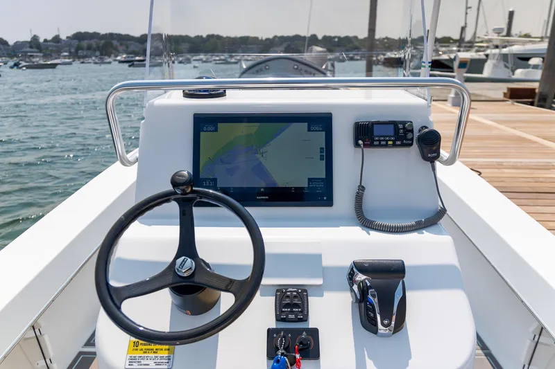 Slide: The Image of 2023 Jones Brothers 23 Cape Fisherman boat dashboard with steering wheel and navigation display. - 23