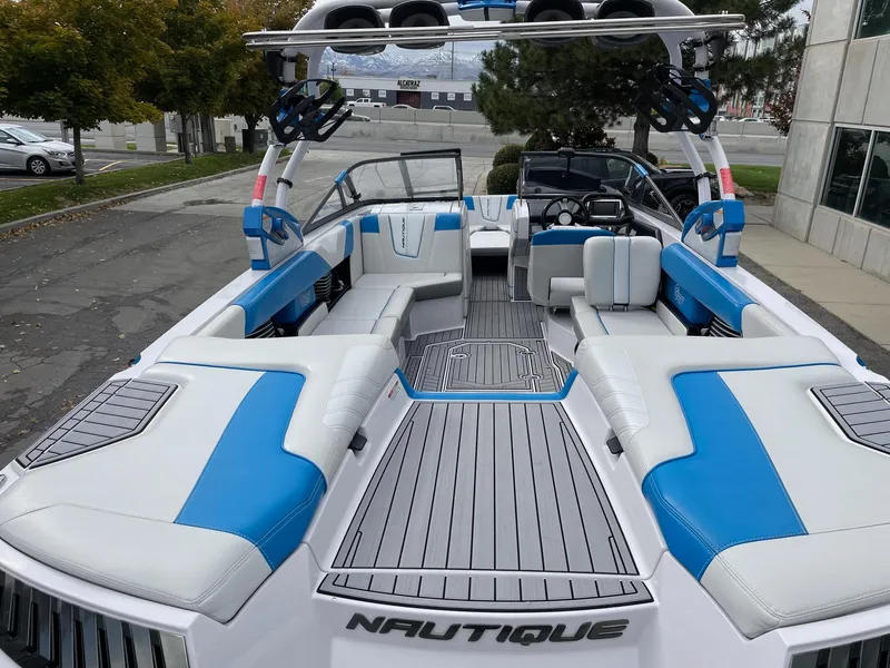Slide: The Image of 2015 Nautique Super Air Nautique G25 boat with blue and white interior, docked outdoors. - 4