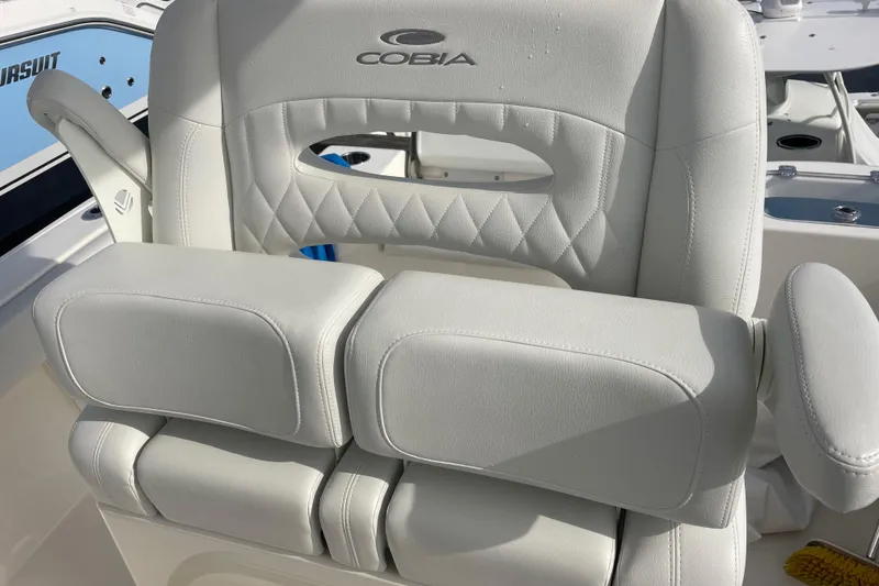 Slide: The Image of Cobia 220 Center Console 2022 boat seat with cushioned armrests and diamond stitching. - 7