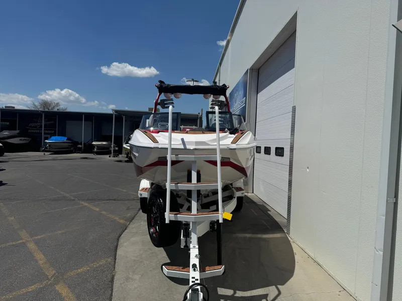 Slide: The Image of 2023 Supra SL 550 boat on trailer outside a building under a clear sky. - 3