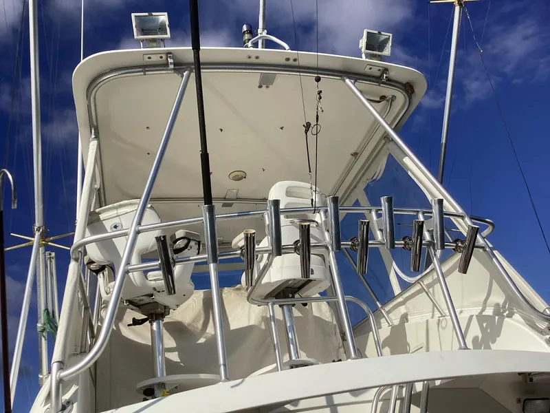 Slide: The Image of 2006 Henriques 35 Flybridge with fishing rod holders against a clear blue sky. - 20
