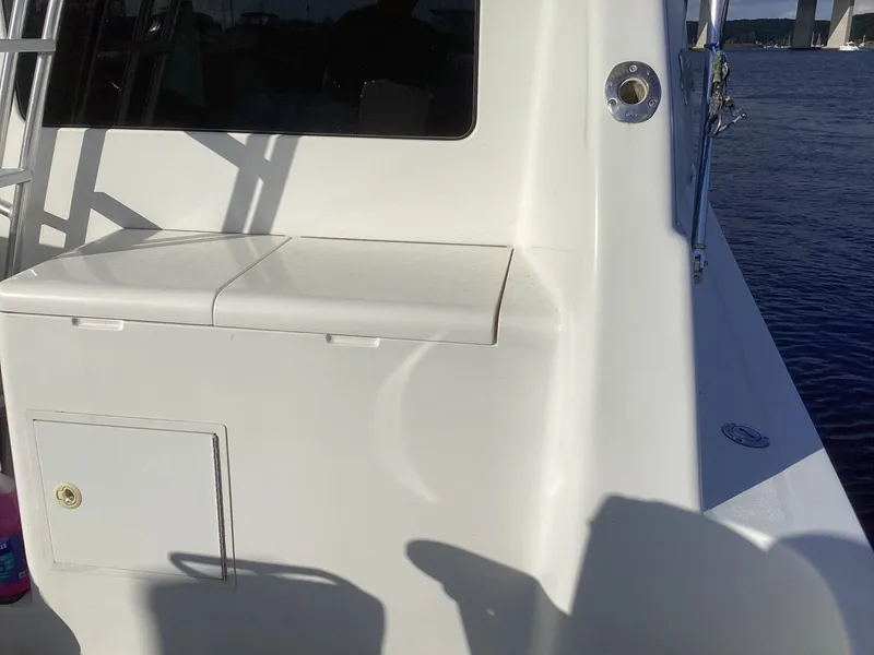 Slide: The Image of Henriques 35 Flybridge 2006 boat deck with storage compartment, docked by the water. - 21