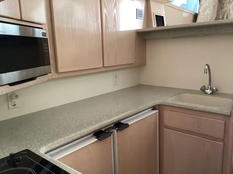 Slide: The Image of 2006 Henriques 35 Flybridge kitchen with microwave, sink, and light wood cabinetry. - 36