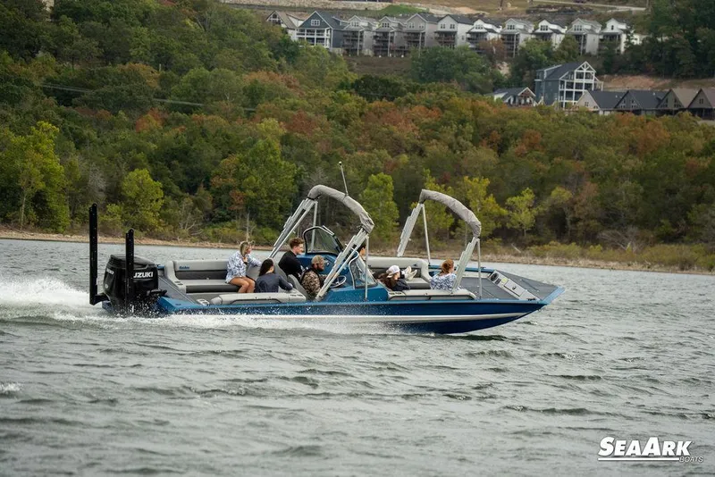 Slide: The Image of 2025 SeaArk Super Lounge Easy boat cruising on a lake with passengers, surrounded by scenic hills. - 3