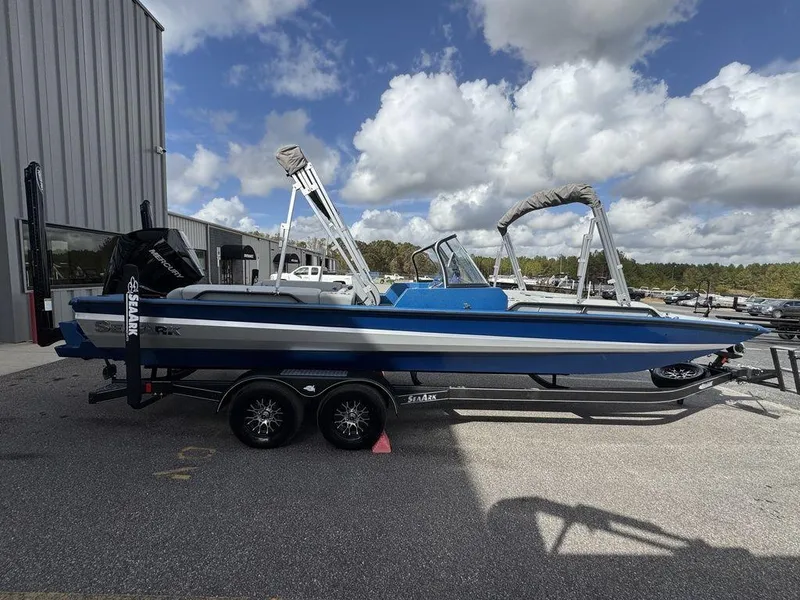Slide: The Image of 2025 SeaArk Super Lounge Easy boat on trailer, parked outdoors under cloudy sky. - 8