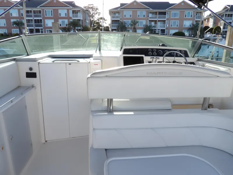 Slide: The Image of 1998 Wellcraft Martinique 3600 boat interior with helm and seating, docked near waterfront homes. - 14