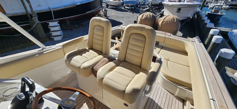 Slide: The Image of 2013 Chris-Craft Catalina 29 Sun Tender with beige seating and wooden accents at a marina. - 5