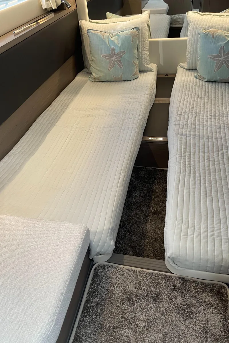 Slide: The Image of Interior of 2025 Jeanneau NC 1295 Coupe with twin beds and decorative pillows. - 15