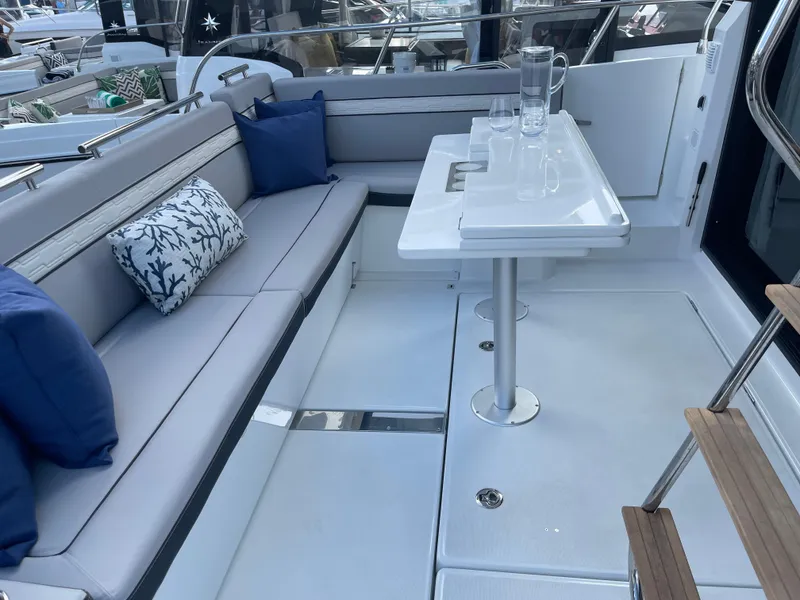 Slide: The Image of 2025 Jeanneau NC 1295 Coupe interior with elegant seating and modern table setup. - 3