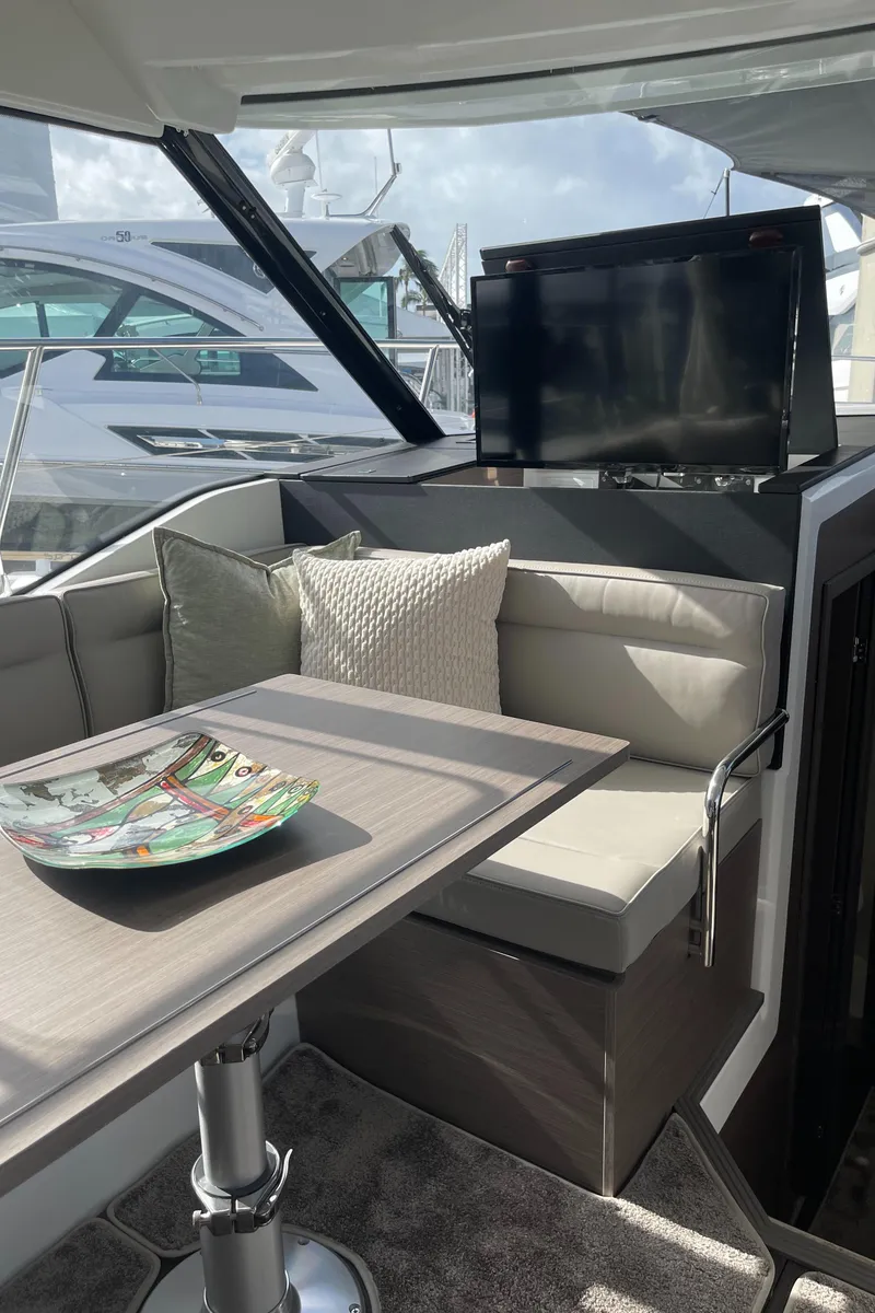 Slide: The Image of 2025 Jeanneau NC 1295 Coupe interior with seating, table, and TV. - 9