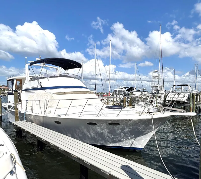 Slide: The Image of 1988 Marine Trader Tradewinds 43 Motor Yacht docked at marina under blue sky. - 1