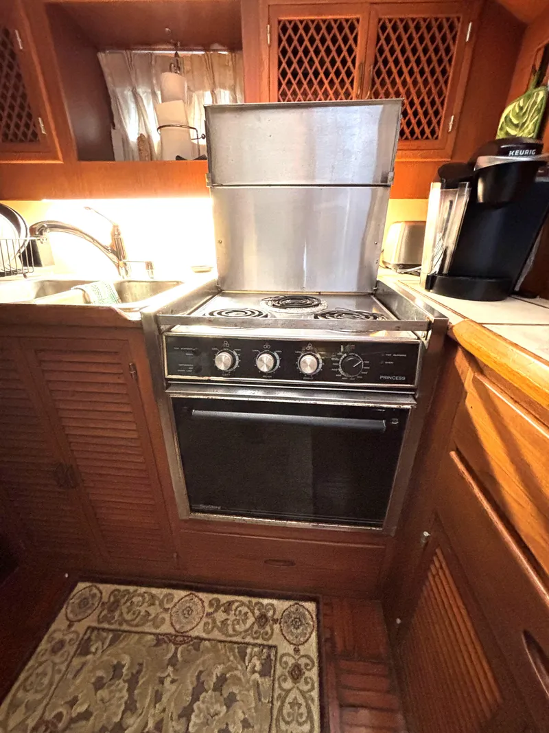 Slide: The Image of 1988 Marine Trader Tradewinds 43 Motor Yacht kitchen with stove and wooden cabinetry. - 42