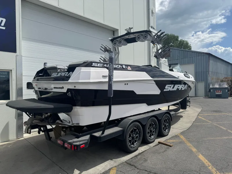 Slide: The Image of 2023 Supra SE 550 boat on trailer, parked outside a warehouse. - 4