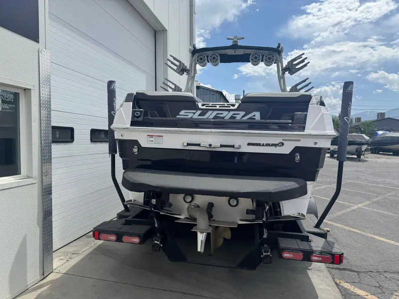 Slide: The Image of 2023 Supra SE 550 boat rear view, parked near a building under a partly cloudy sky. - 6