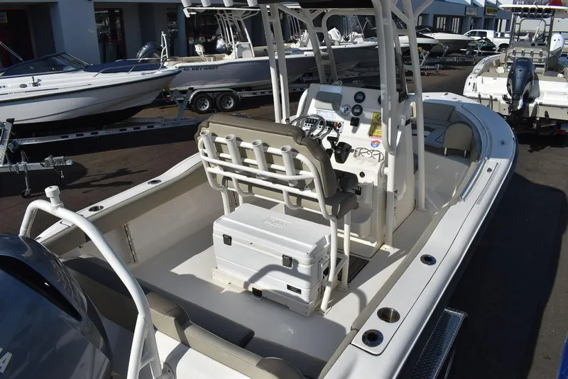 Slide: The Image of 2022 Key West 219fs boat interior with seating and console, parked in a marina. - 11