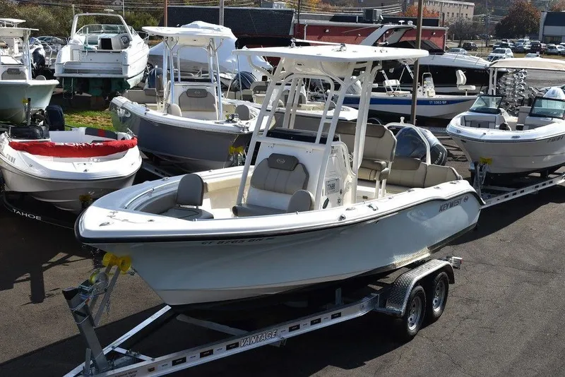 Slide: The Image of 2022 Key West 219fs boat on trailer, surrounded by other boats in a marina. - 2