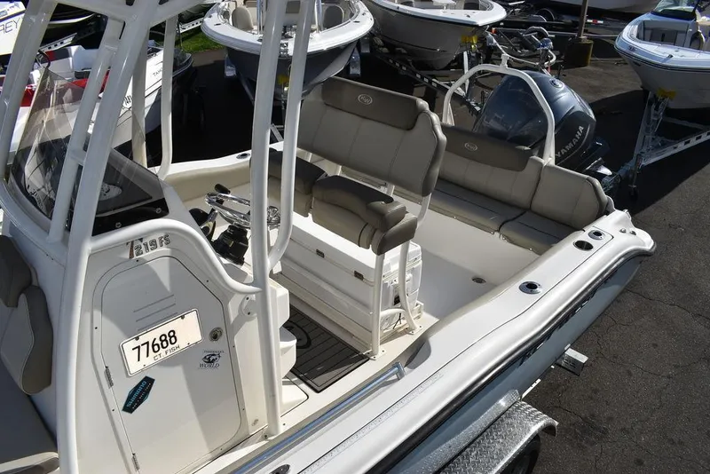 Slide: The Image of 2022 Key West 219fs boat interior with seating and console, displayed outdoors. - 24
