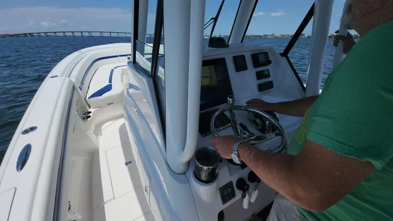 Slide: The Image of 2015 Intrepid 327 Center Console boat on water, person steering, bridge in background. - 31