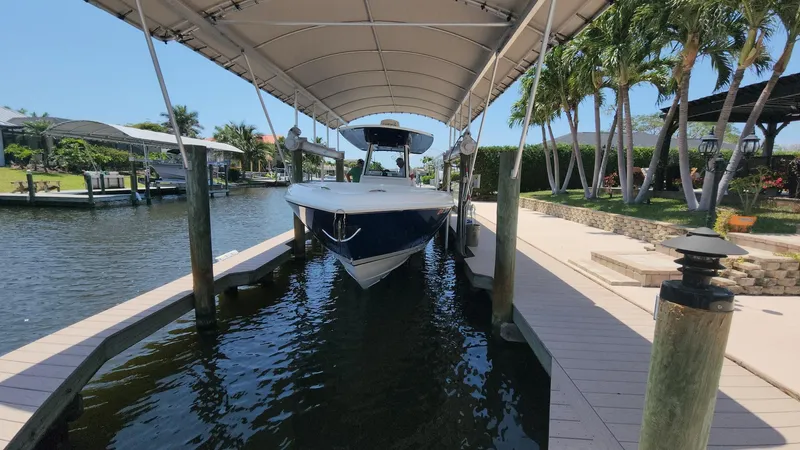 Slide: The Image of 2015 Intrepid 327 Center Console boat docked under canopy in sunny marina. - 33