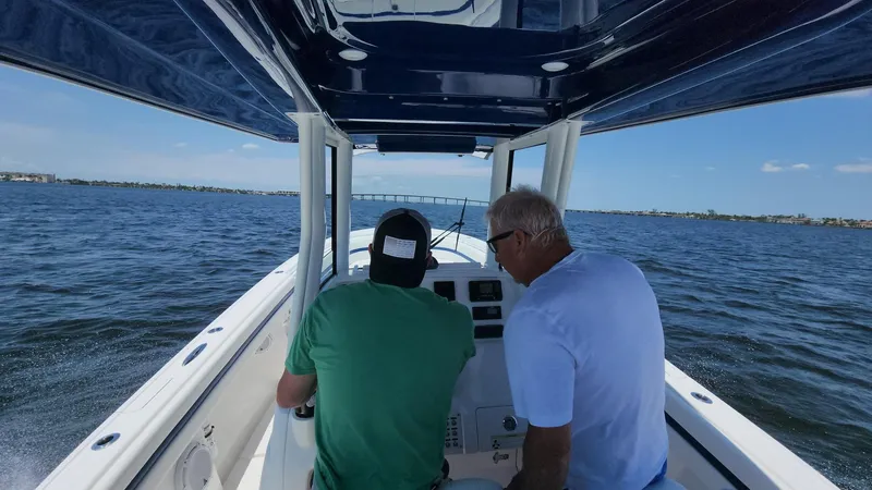 Slide: The Image of Two people navigating a 2015 Intrepid 327 Center Console boat on open water. - 47