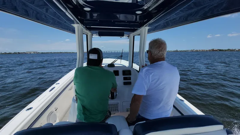 Slide: The Image of Two people navigating a 2015 Intrepid 327 Center Console boat on open water. - 48
