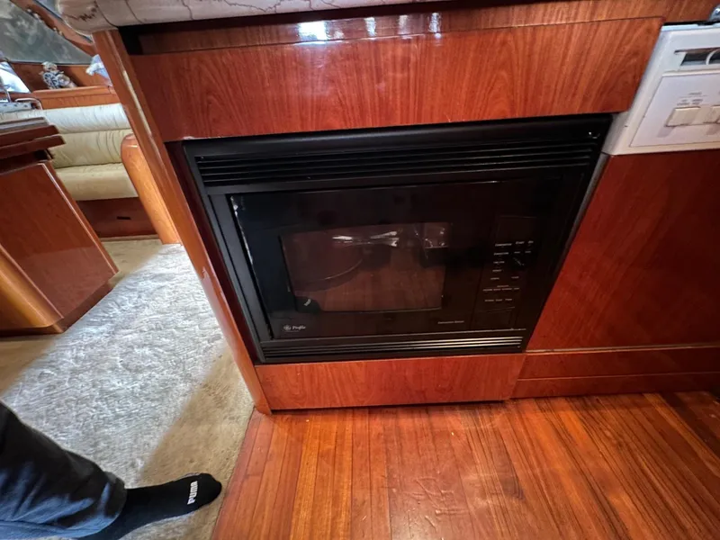 Slide: The Image of Wood-paneled kitchen with built-in microwave on a 2001 Johnson 70 yacht. - 14